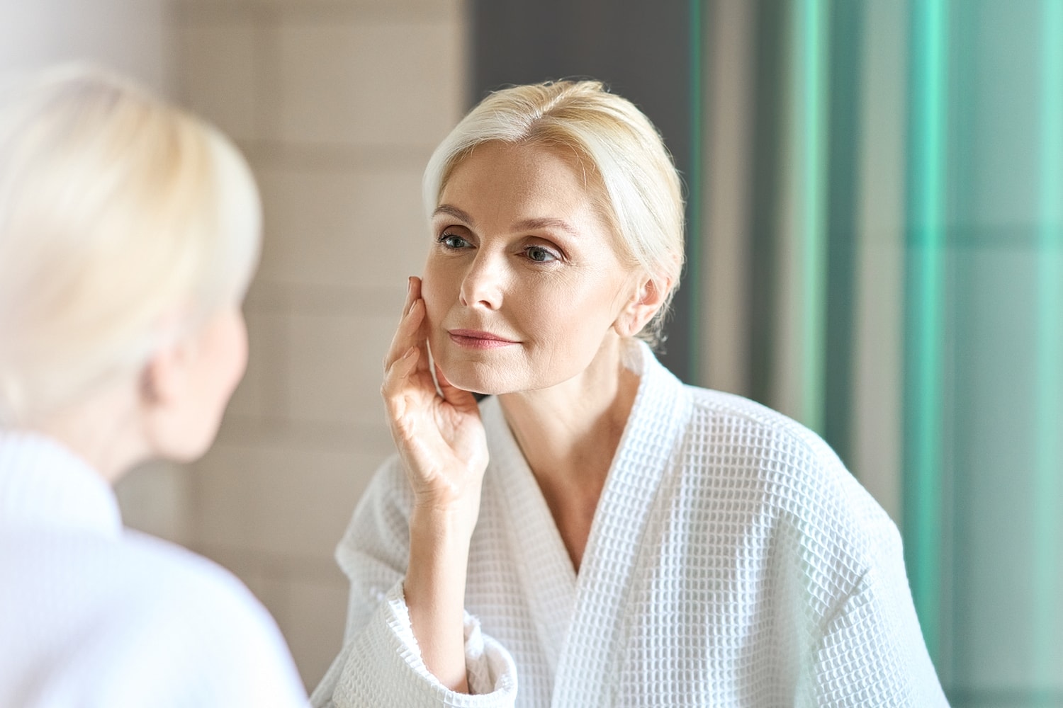 Woman examining her skin in bathroom mirror.
