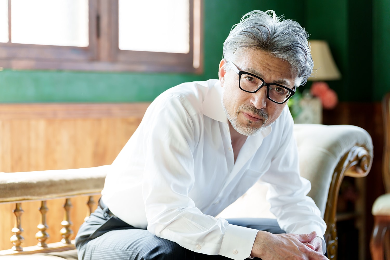 Man in white shirt seated, looking thoughtfully.