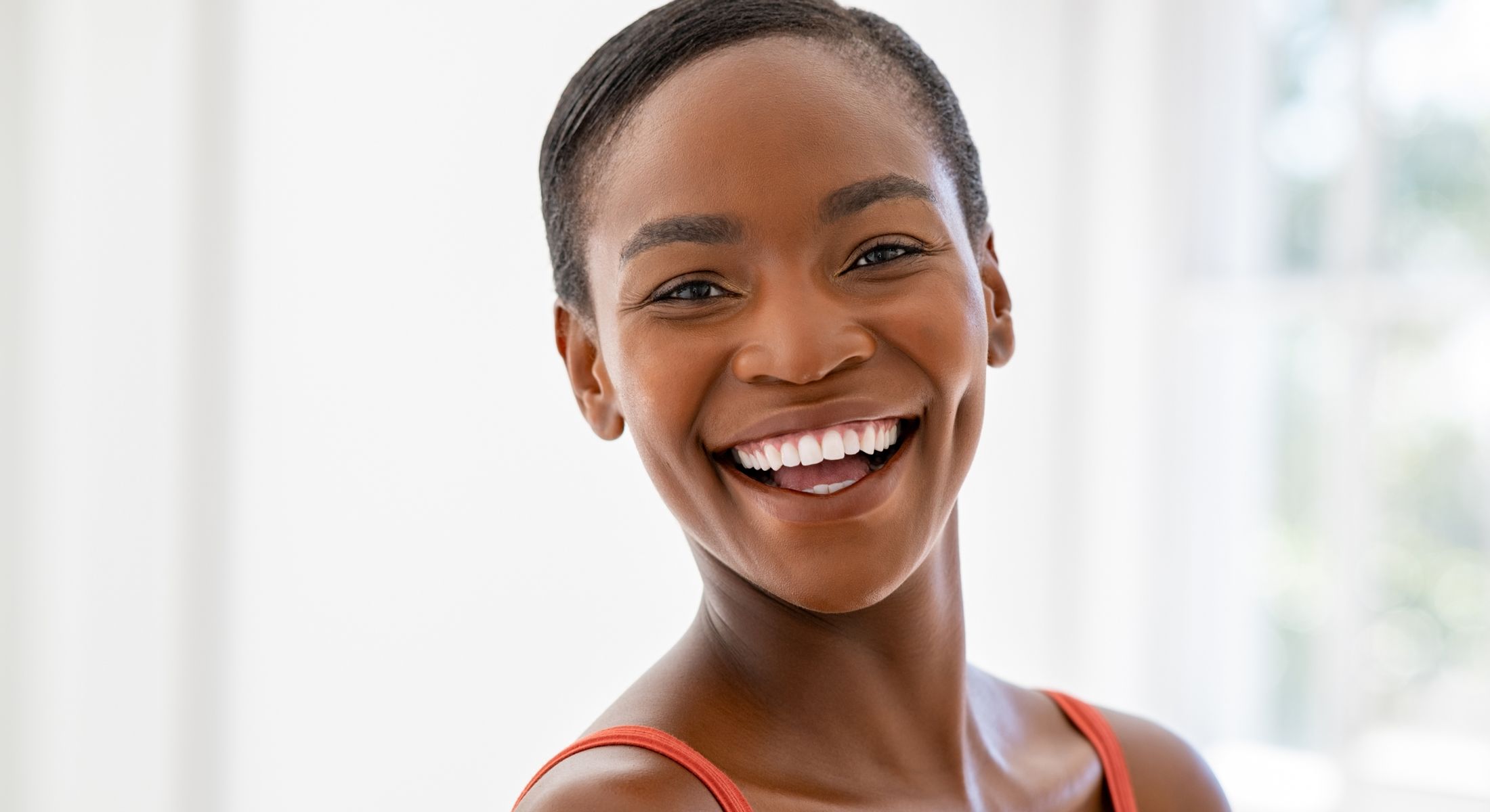 Smiling woman in natural light, joyful expression.