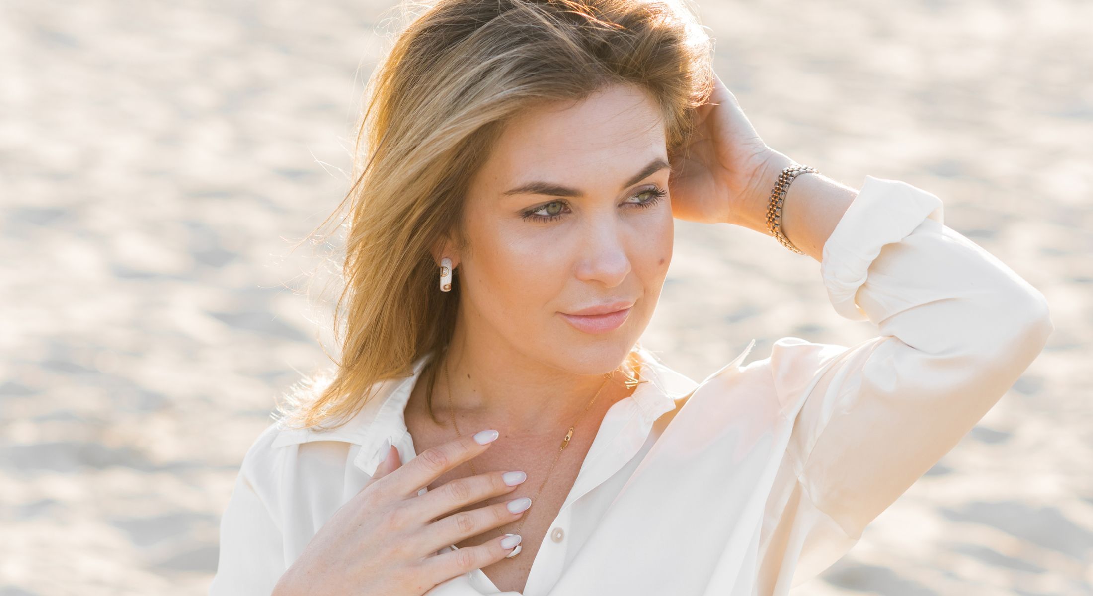 Woman with blonde hair posing on the beach.