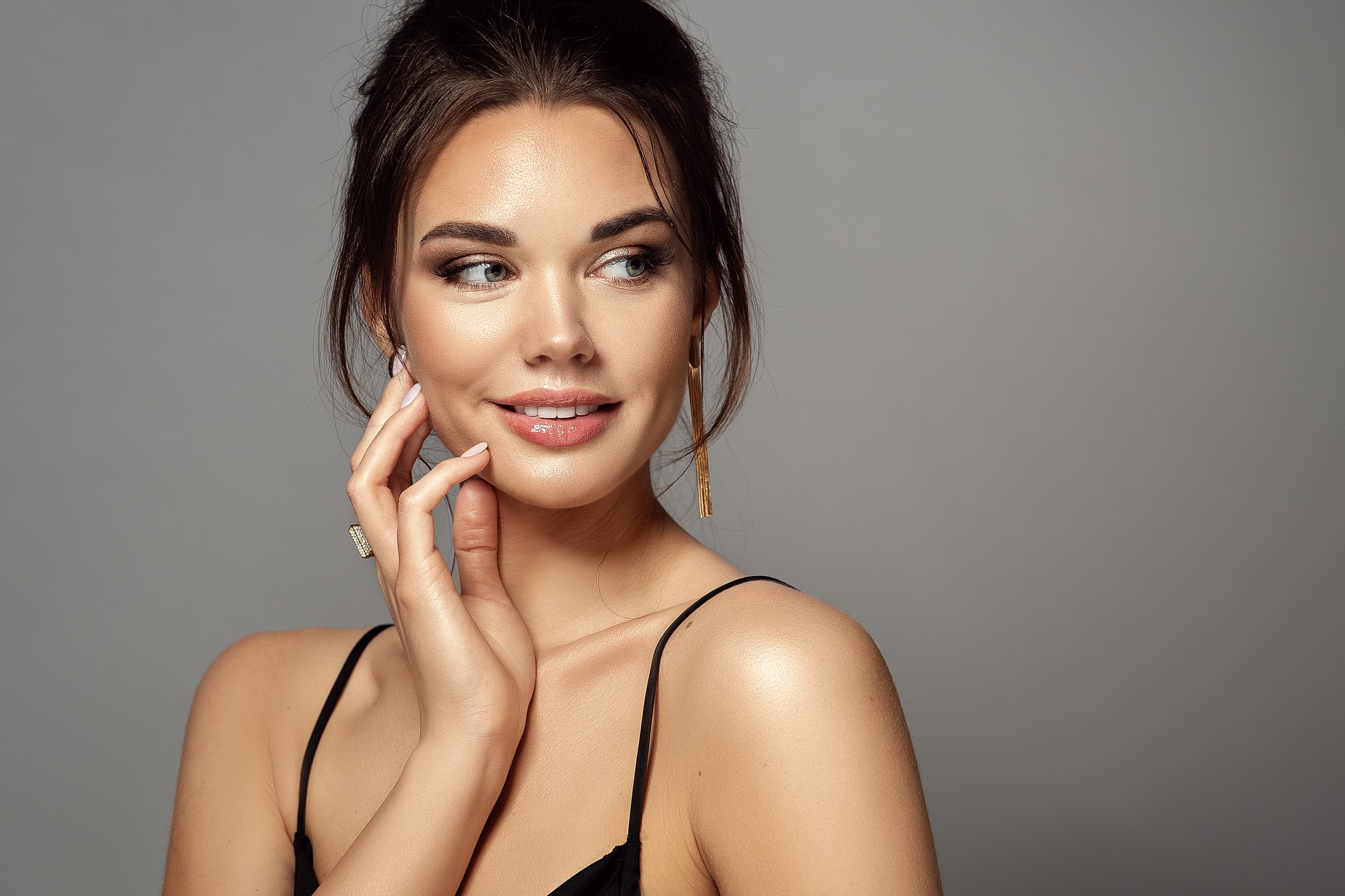 Smiling woman with elegant hairstyle and jewelry.