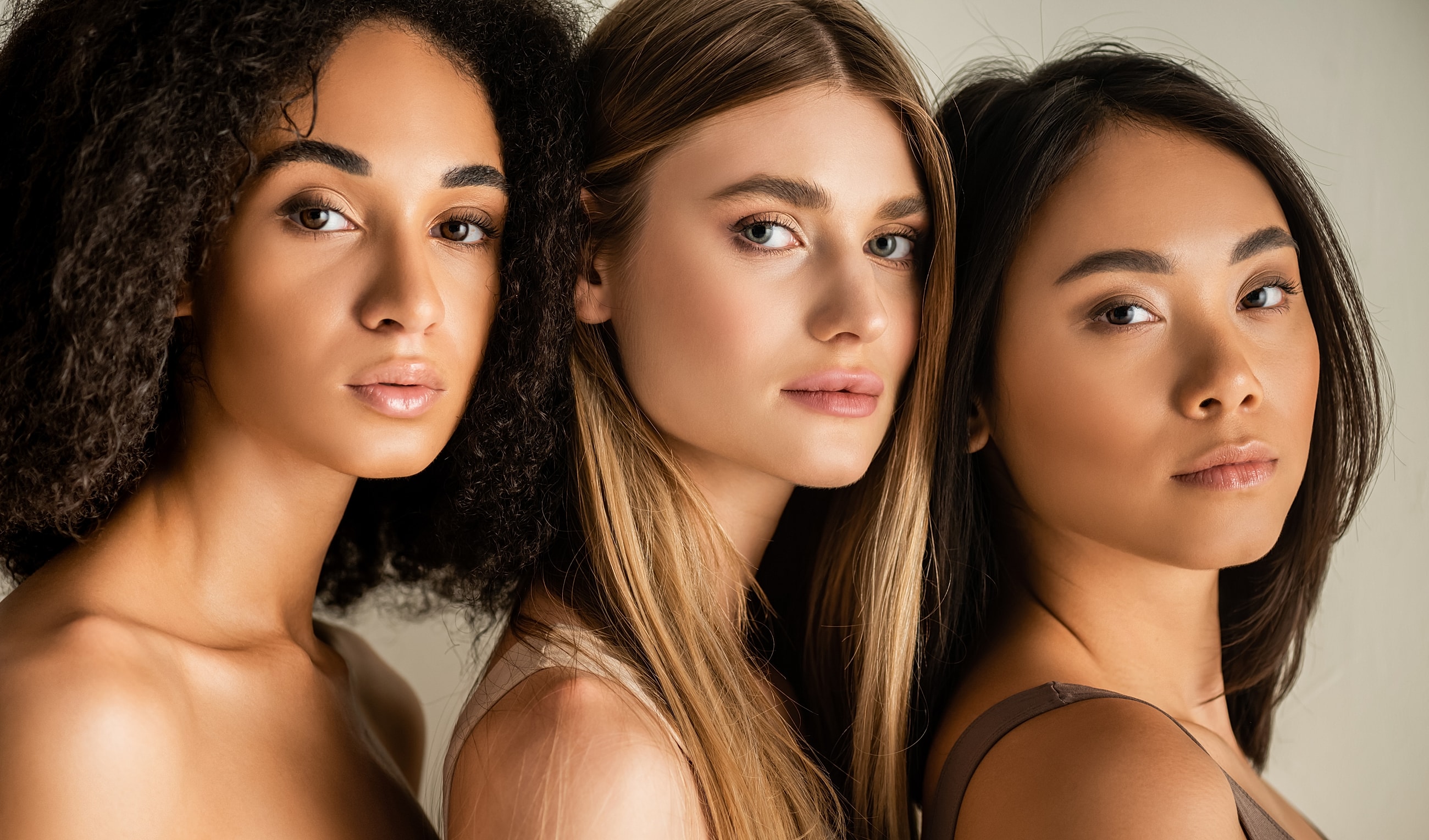 Three women with diverse hairstyles and skin tones.