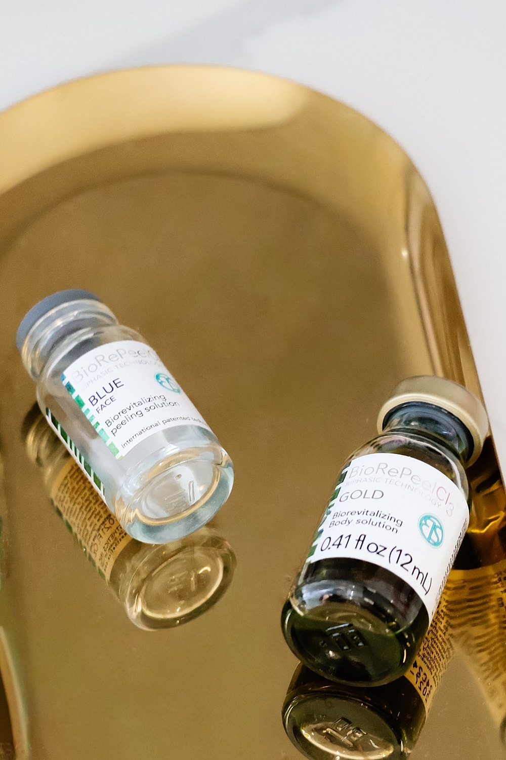 Two vials of skincare solutions on a tray